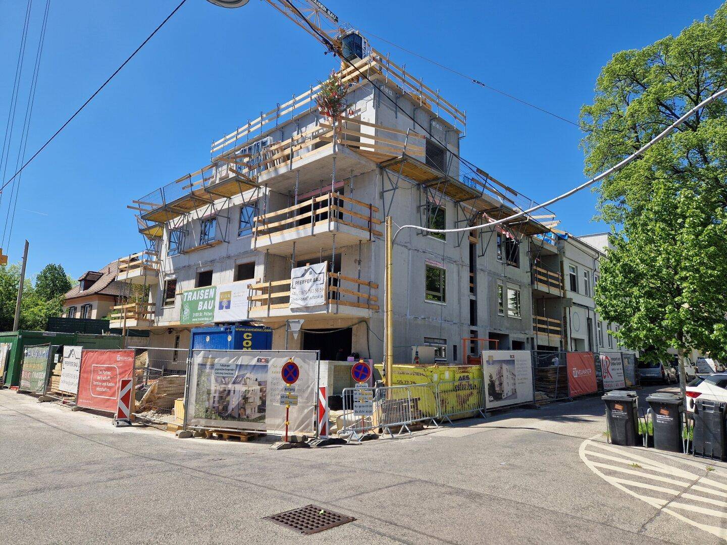 Neubauprojekt im Bauzustand mit Gerüst und Baukran unter blauem Himmel.