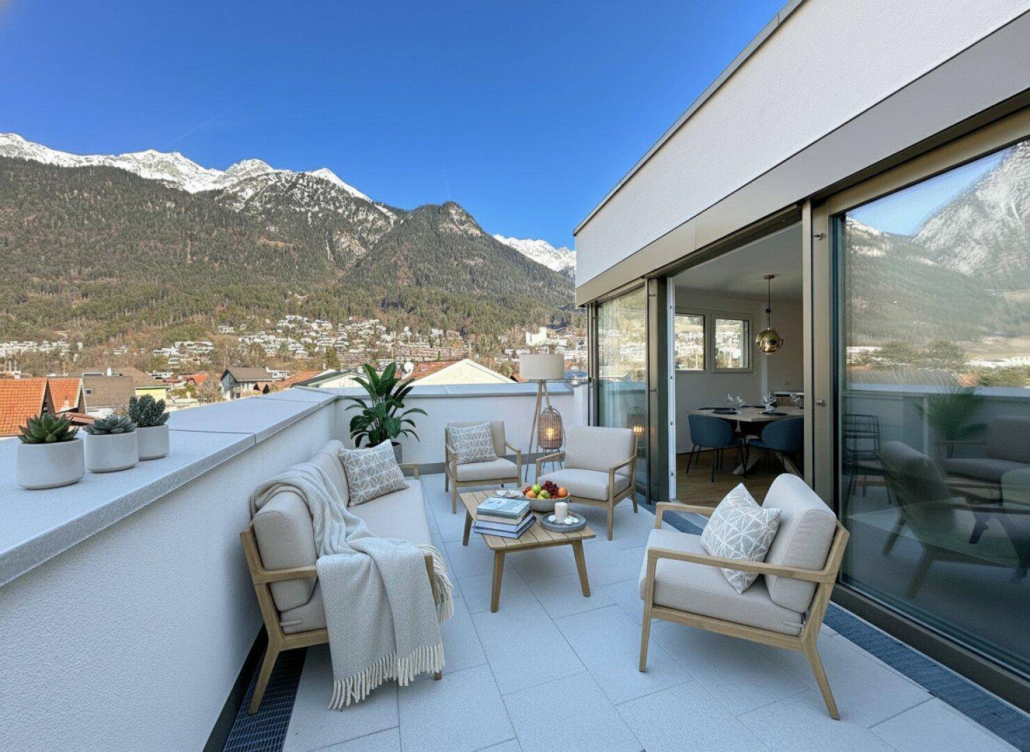 Geräumige Dachterrasse mit komfortablen Gartenmöbeln und spektakulärem Panoramablick auf die schneebedeckten Berge.