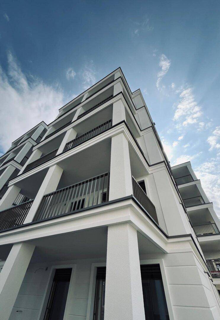 Architektonische Perspektive eines modernen Wohngebäudes mit vielen Balkonen und einer klaren Linienführung.