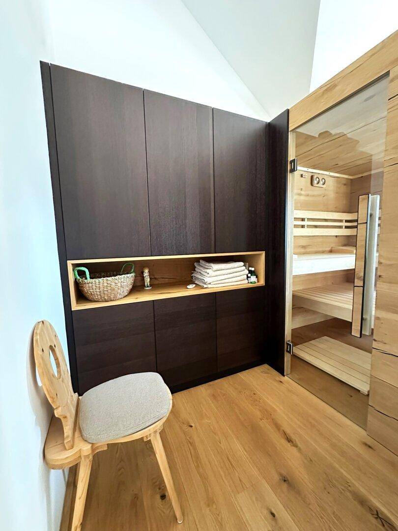 Bereich neben der Sauna mit Holzboden und Einbauschränken, ideal für Handtücher und Bademäntel.
