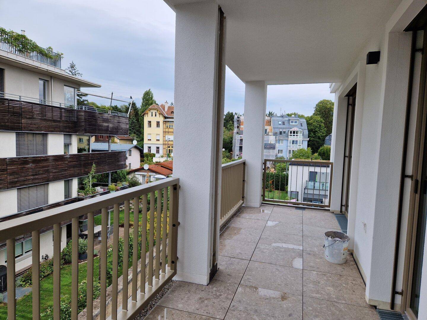 Geräumige Loggia mit Fliesenboden und weitem Blick über die Wohngegend.