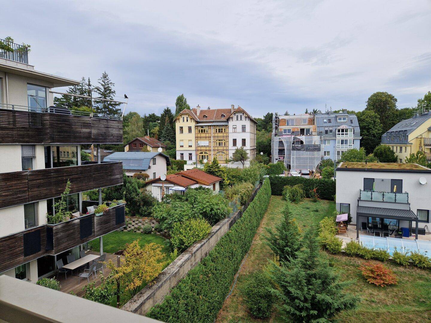 Weitblick über eine Wohngegend mit Gärten, Häusern und einem Pool von einem Balkon aus.