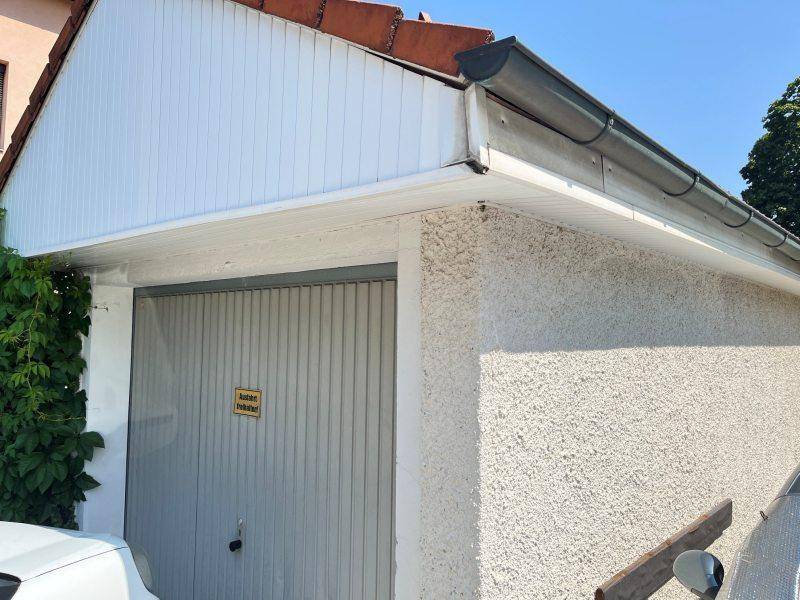 Außenansicht einer Garage mit Putzfassade und Satteldach des angrenzenden Hauses.