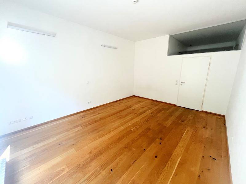 Geräumiges, helles Zimmer mit Holzboden und einer hohen Decke.
