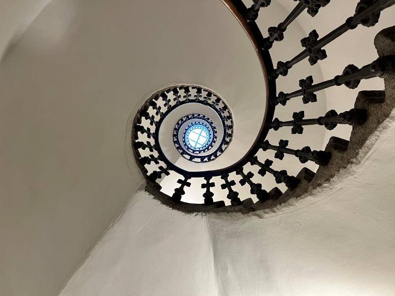 Elegante Wendeltreppe mit kunstvollem Geländer, die sich spiralförmig nach oben windet und ein Oberlicht zeigt.