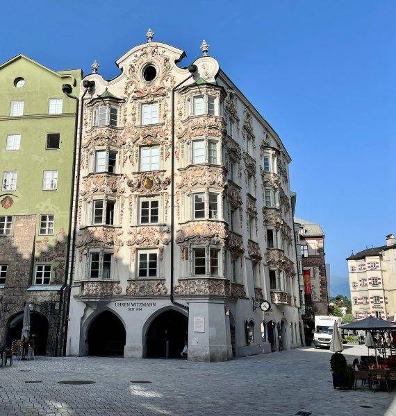 Historisches Gebäude mit reich verzierter Fassade und traditioneller Architektur in einer belebten städtischen Umgebung.
