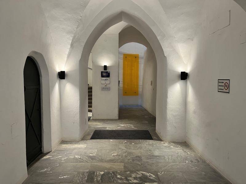 Historischer Eingangsbereich mit beeindruckenden Gewölbedecken und Steinboden, der zu weiteren Räumen führt.
