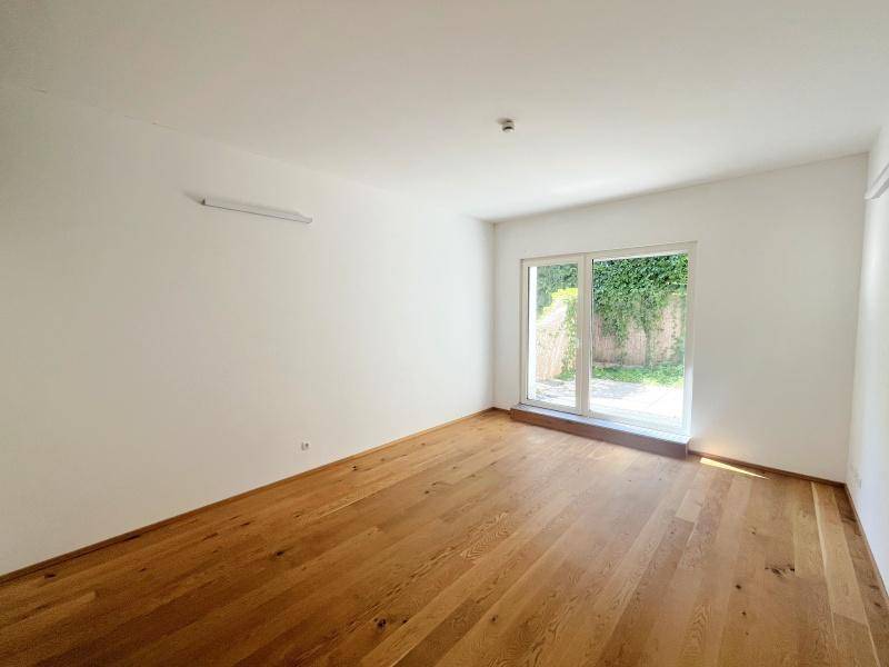 Lichtdurchflutetes Zimmer mit Holzboden und Zugang zu einem privaten Außenbereich.