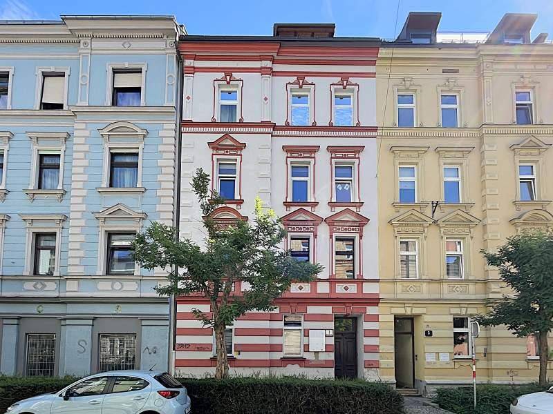 Historische Fassade eines Mehrfamilienhauses mit markanten roten und weißen Streifen in einer städtischen Umgebung.
