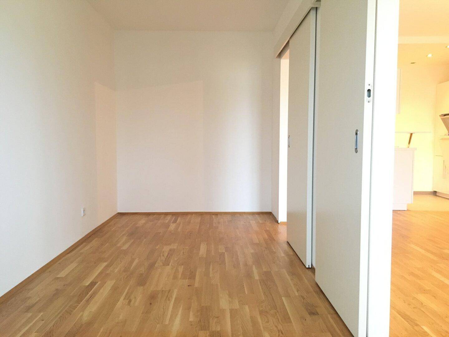 Geräumiger, leerer Raum mit hellem Holzboden und weißen Wänden, ideal für individuelle Gestaltung.