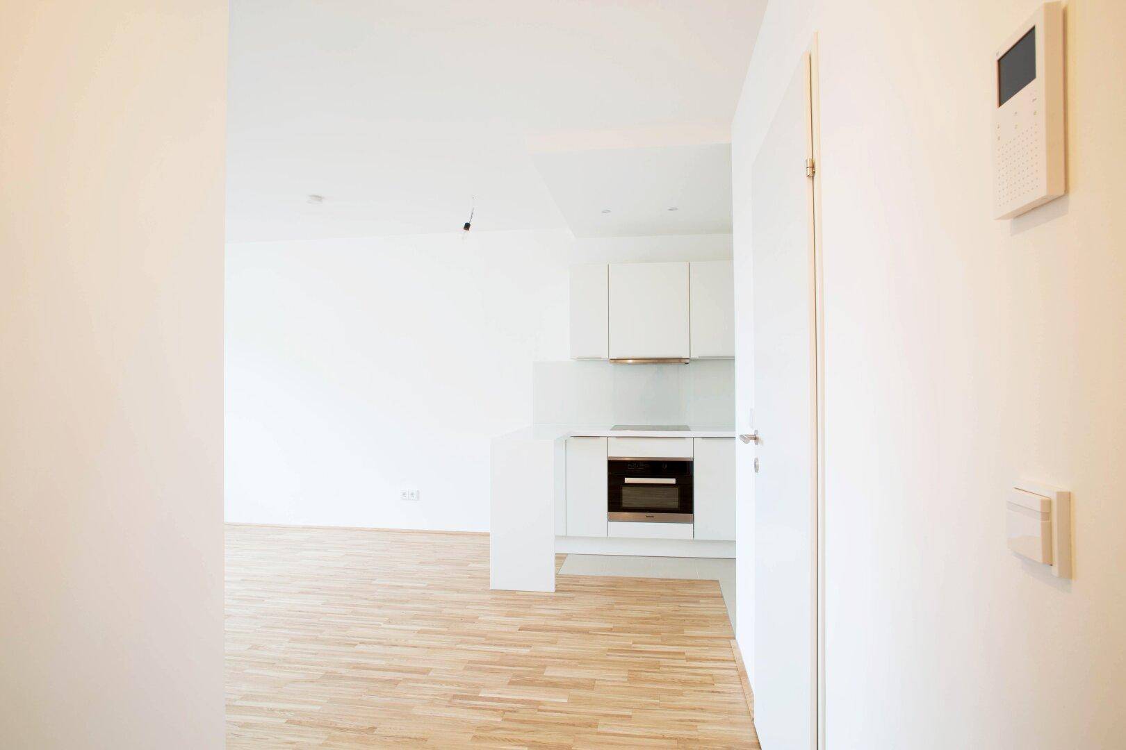 Eingangsbereich mit Blick auf die offene Küche und moderne Gegensprechanlage.