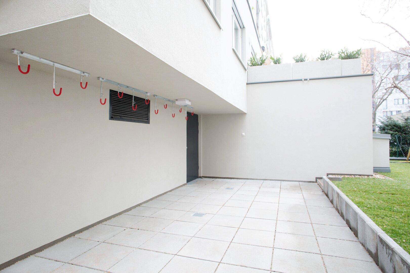 Ebenerdige Terrasse mit Fliesenboden und angrenzender Grünfläche, ideal für Fahrräder.
