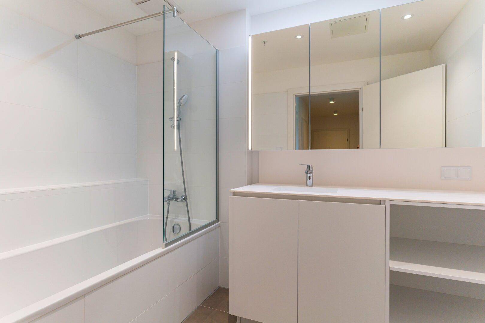 Modernes Badezimmer mit Badewanne, Duschabtrennung und Spiegelschrank in hellem Design.