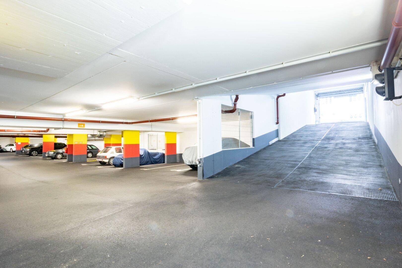 Einfahrt zur Tiefgarage mit Rampe und ausreichend Parkplätzen für Bewohner.