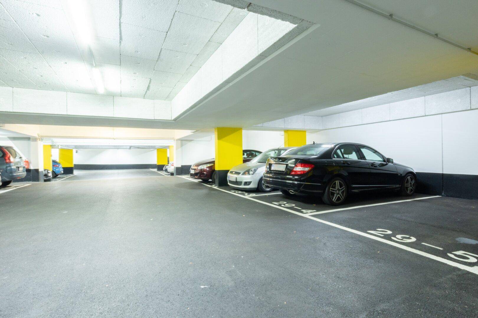 Saubere Tiefgarage mit nummerierten Parkbuchten, gelben Säulen und Betonboden.
