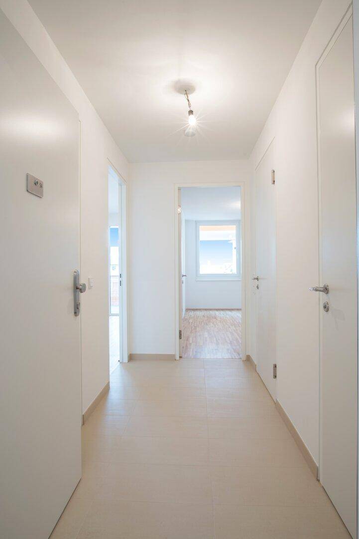 Heller Flur mit Fliesenboden, der zu verschiedenen Zimmern der Wohnung führt.