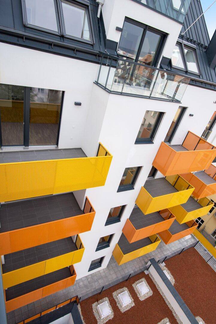 Moderne Balkone mit gelben und orangefarbenen Brüstungen an der Gebäudefassade.