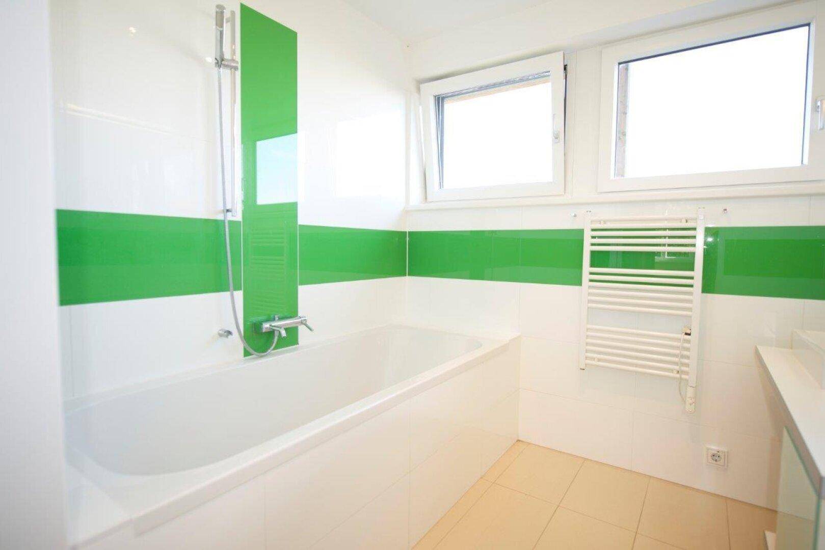 Helles Badezimmer mit Badewanne, Duschfunktion und beheiztem Handtuchhalter.