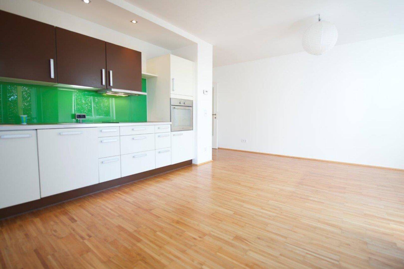 Geräumiger Wohnbereich mit offener Küche, Parkettboden und hellem Ambiente.