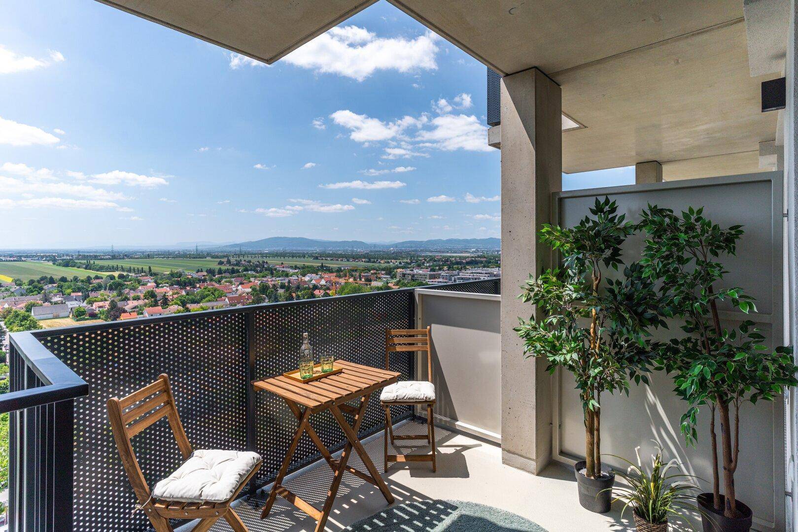 Sonniger Balkon mit Sitzgelegenheiten und weitem Blick über die Landschaft.
