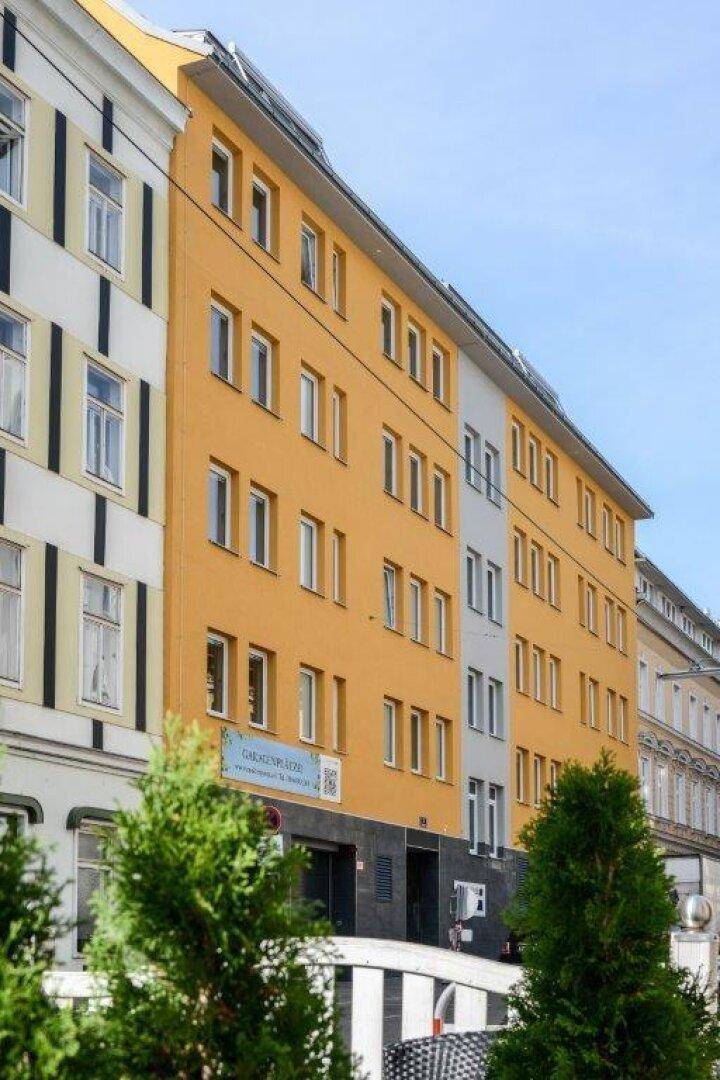 Gelbe Fassade eines modernen Mehrfamilienhauses mit vielen Fenstern und Balkonen.