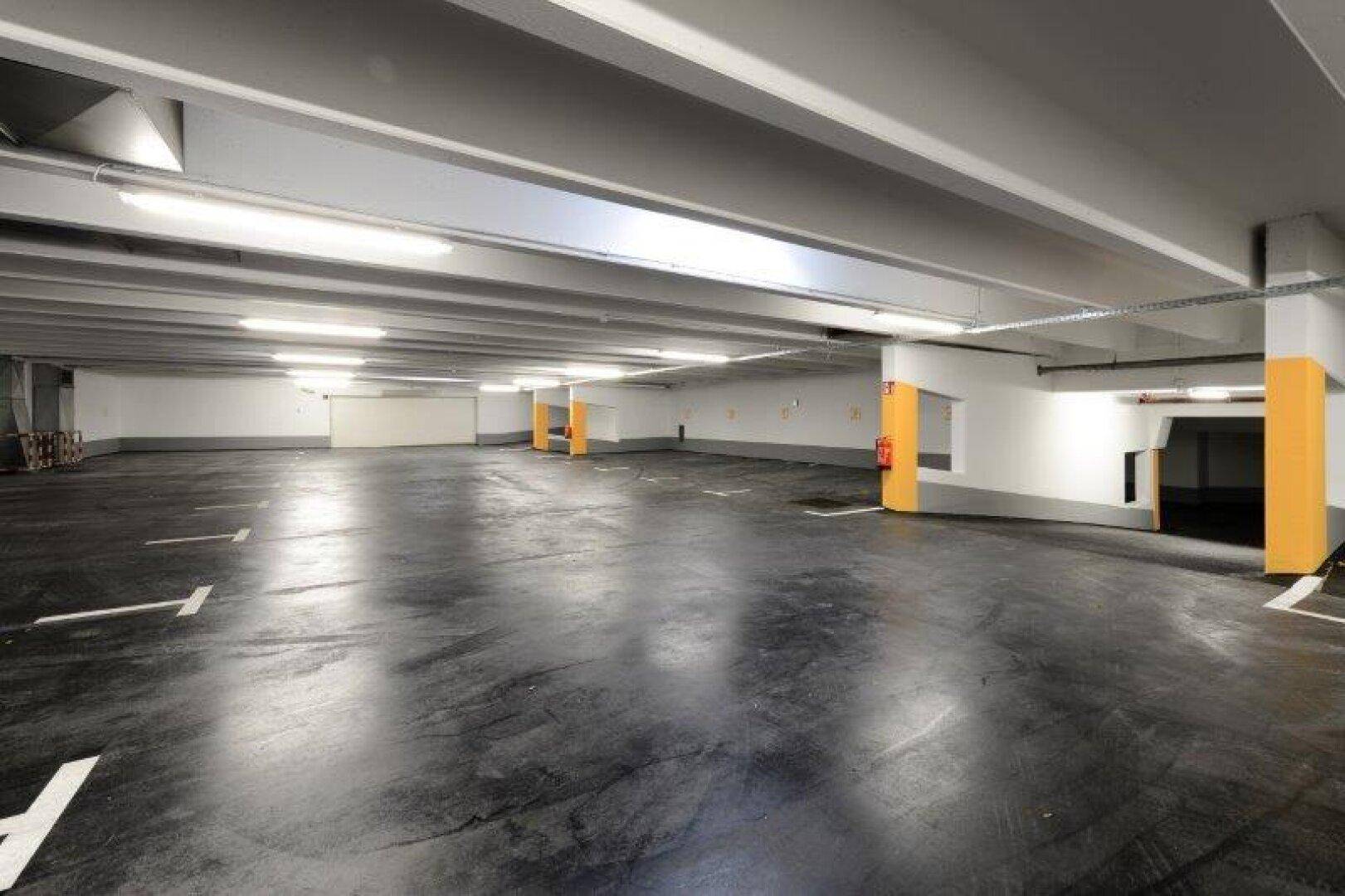 Weitläufige Tiefgarage mit vielen Stellplätzen und klarer Beschilderung.