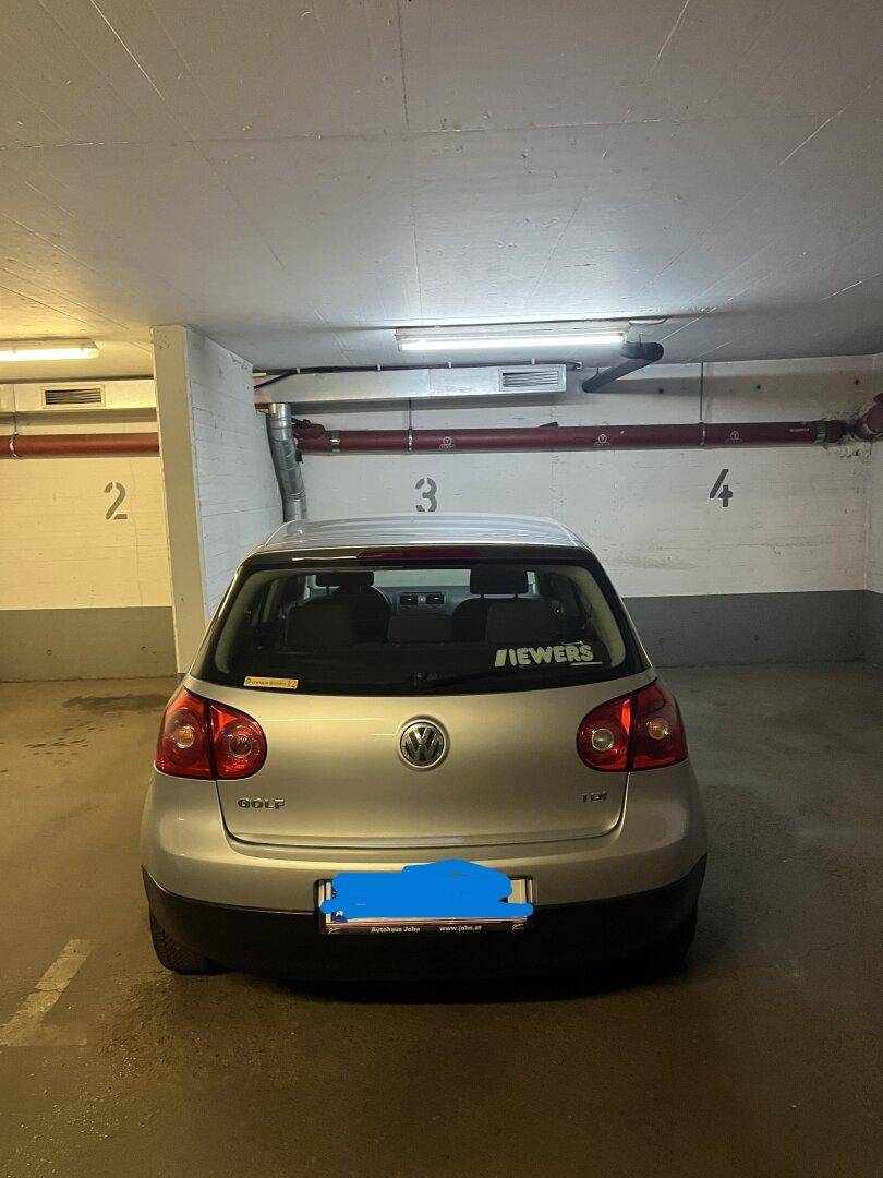 Tiefgarage mit einem geparkten Auto und nummerierten Stellplätzen an der Wand.