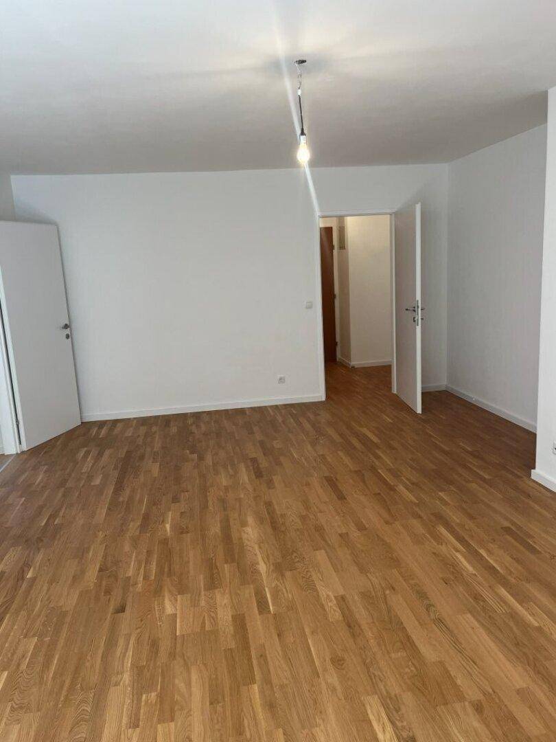 Geräumiges Wohnzimmer mit hellem Parkettboden und weißen Wänden, bereit zur individuellen Gestaltung.