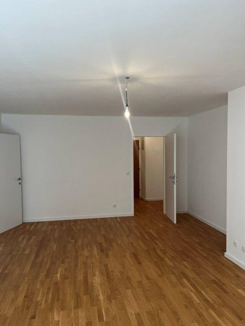 Heller Wohnbereich mit Parkettboden und weißen Wänden, der vielseitige Einrichtungsmöglichkeiten bietet.