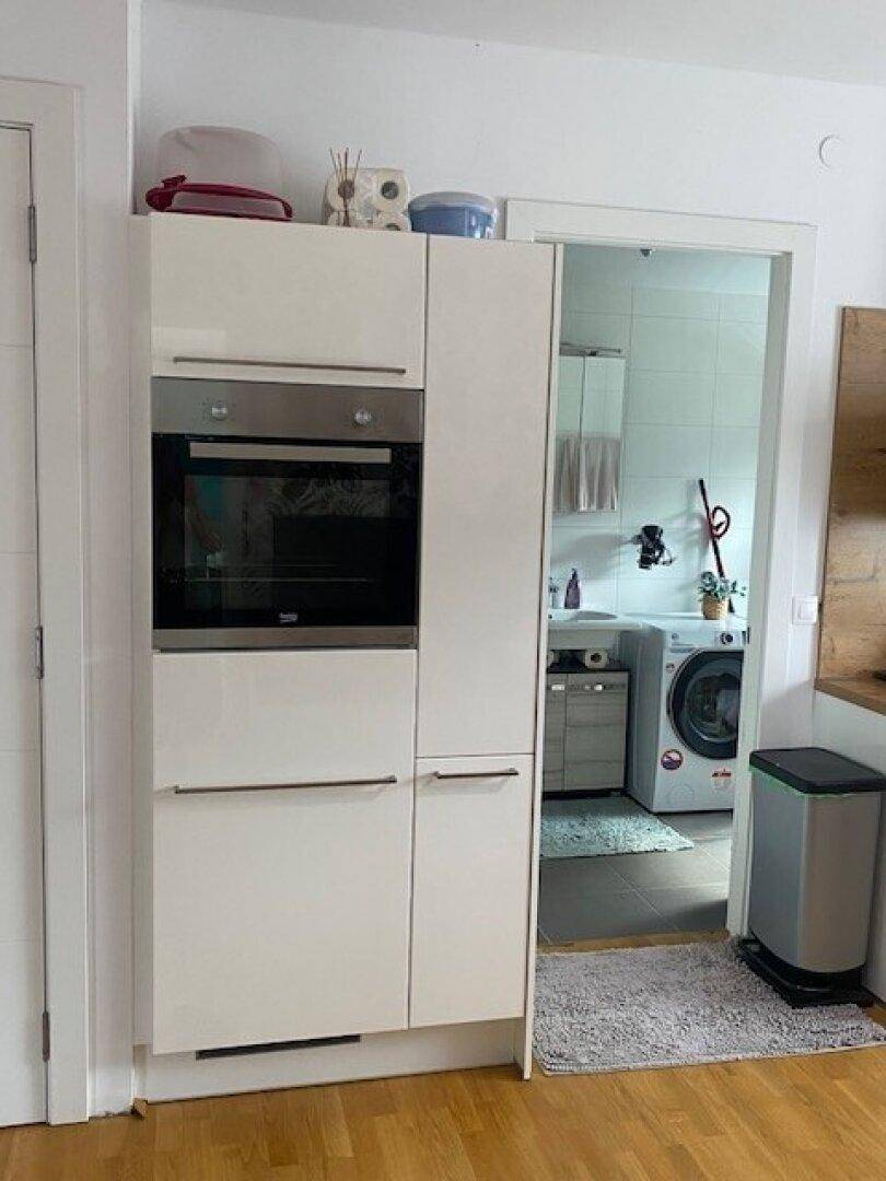 Einbauofen und Schränke in der Küche mit Blick in den angrenzenden Hauswirtschaftsraum.