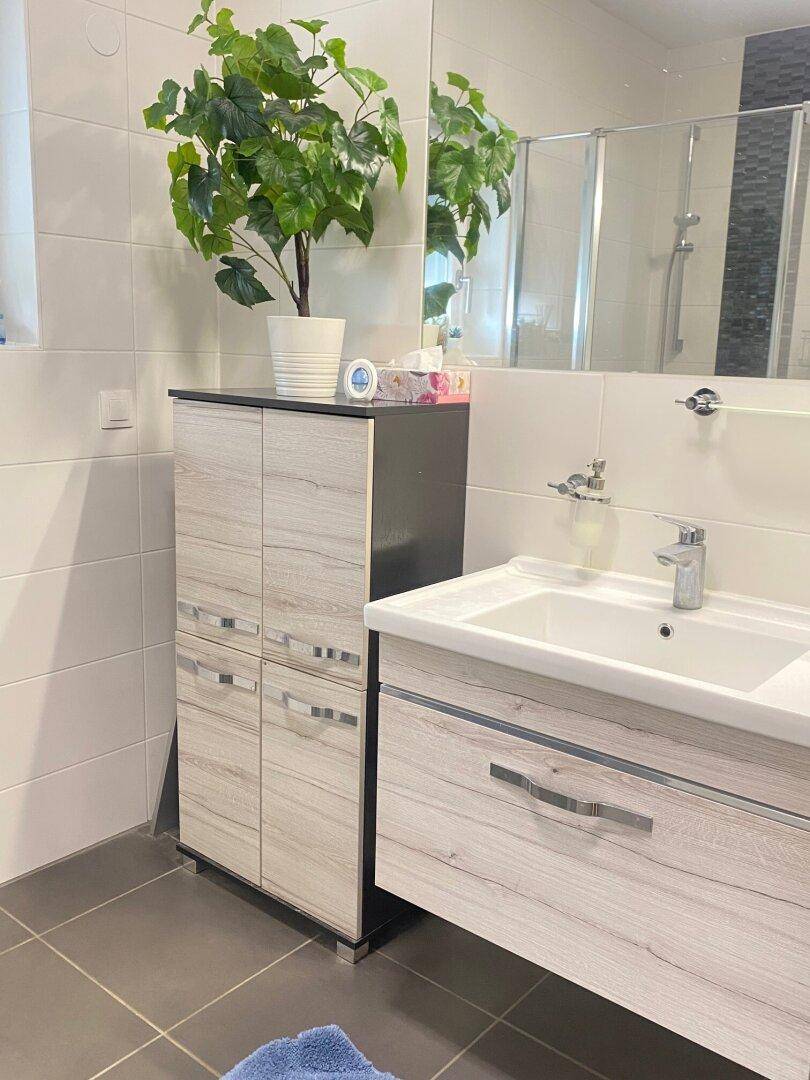 Badezimmer mit modernem Waschbecken, Waschtischunterschrank und großem Spiegel.