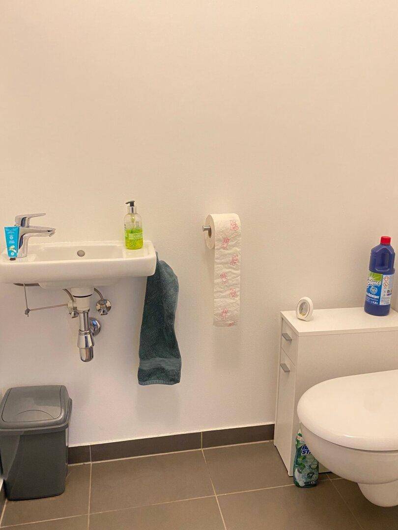 Kleines Gäste-WC mit Waschbecken und wandhängender Toilette, gefliestem Boden.