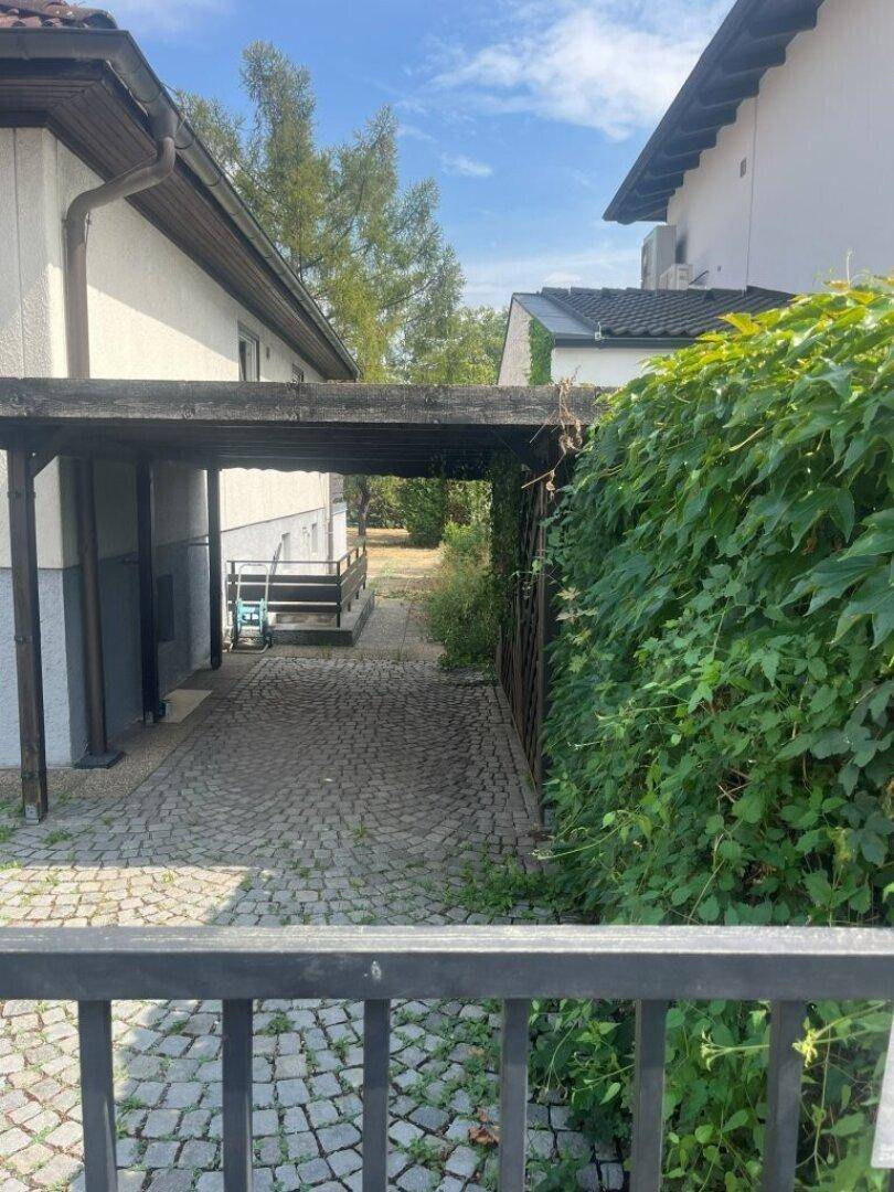 Überdachter Stellplatz und gepflasterter Weg zwischen den Häusern.