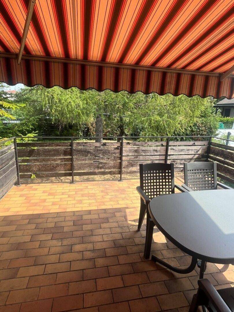 Gemütliche Terrasse mit Markise und Gartenmöbeln, ideal für entspannte Stunden im Freien.