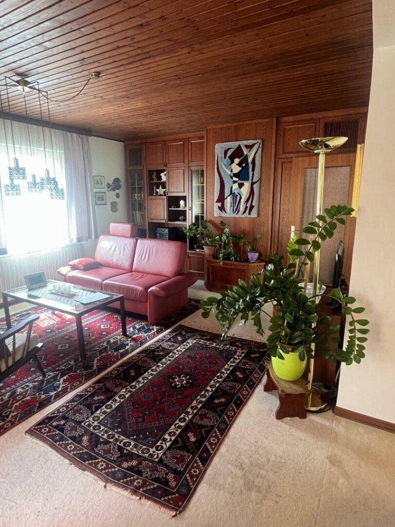 Geräumiges Wohnzimmer mit Holzdecke, Teppichen und traditionellen Holzmöbeln.