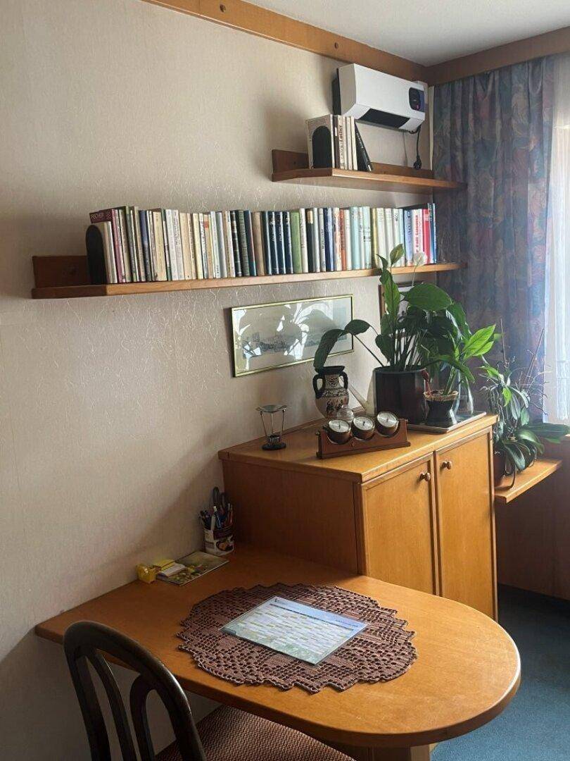 Kleiner Arbeitsbereich mit Schreibtisch, Bücherregalen und Klimaanlage.