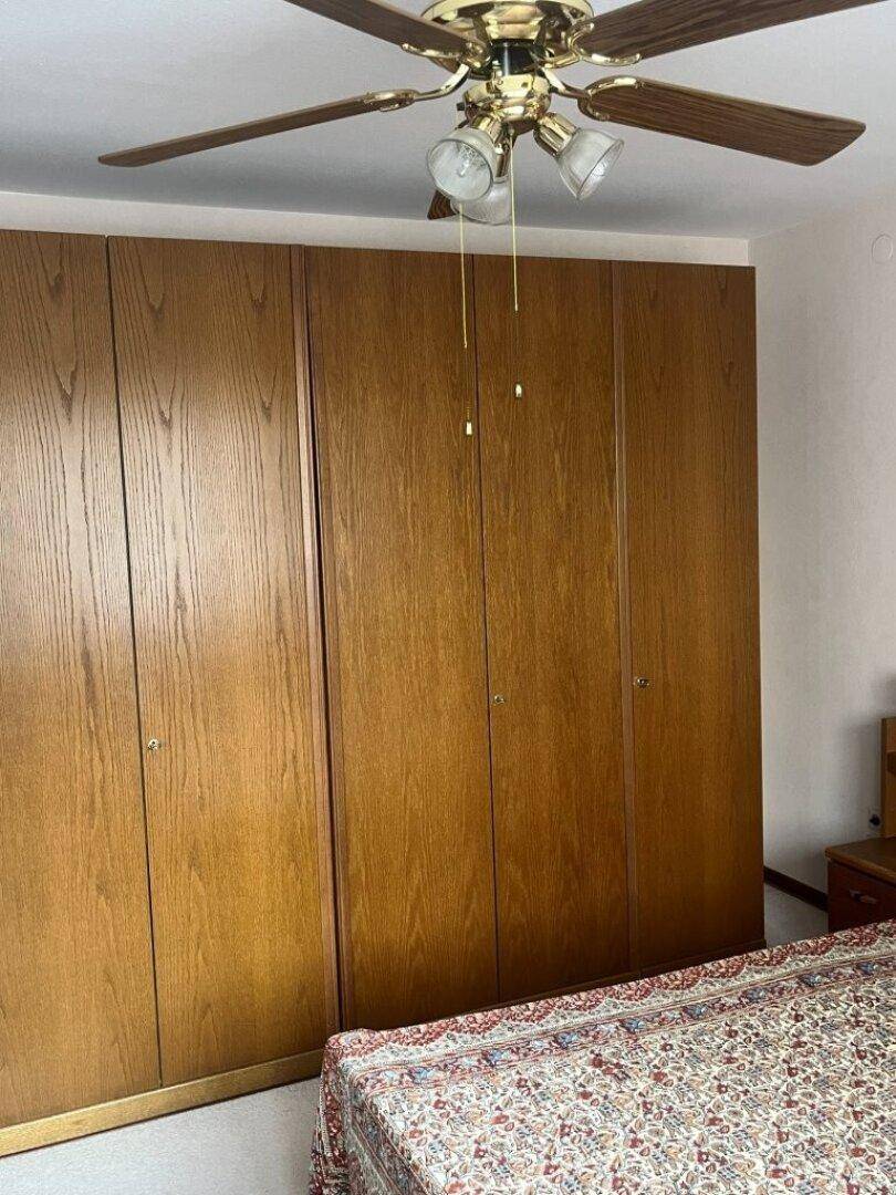Schlafzimmer mit geräumigen Einbauschränken und Deckenventilator.