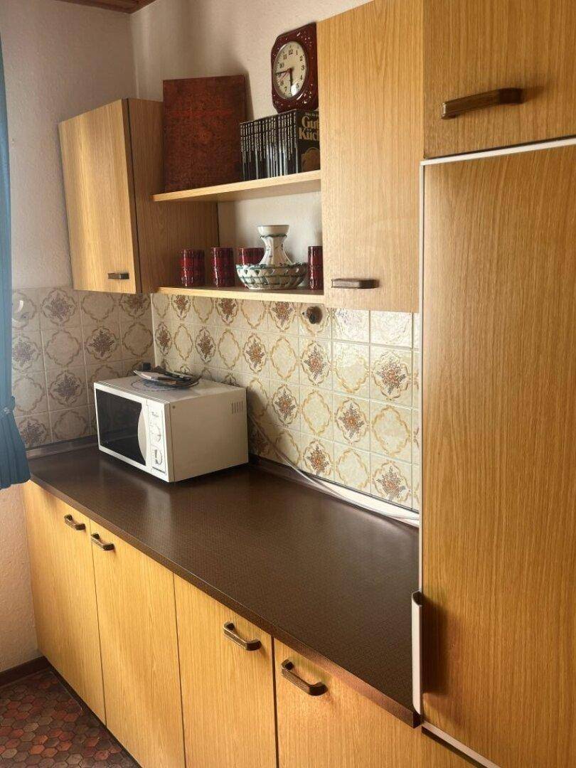 Küche mit Holzschränken, Mikrowelle und integriertem Kühlschrank.