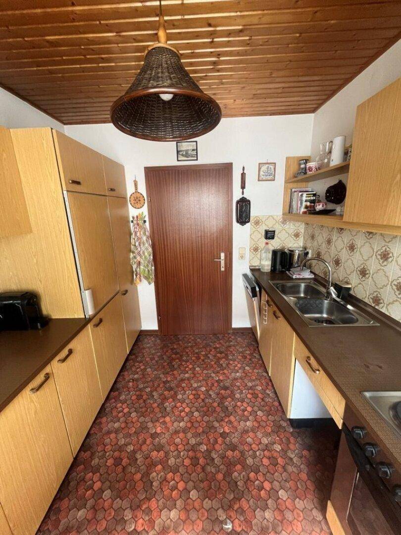 Küche mit Holzschränken, gemustertem Boden und Deckenlampe.