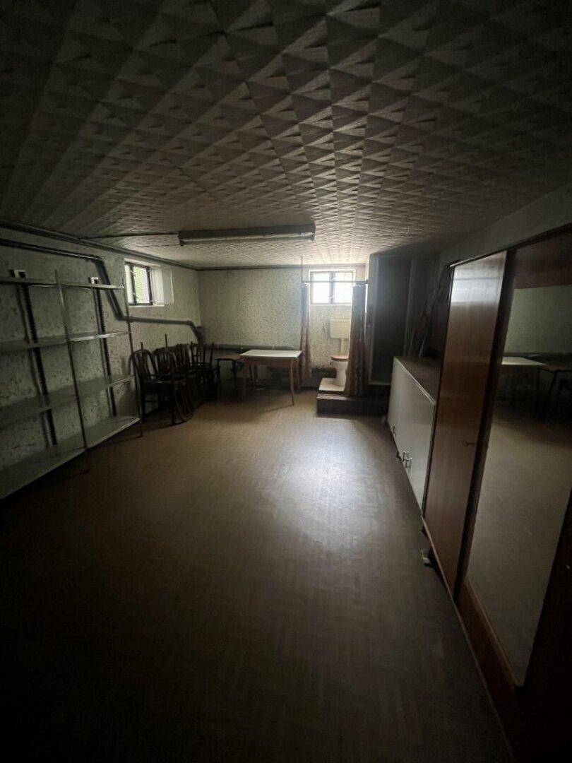 Großer, dunkler Kellerraum mit Regalen, Möbeln und gemusterter Decke, nutzbar als Lager oder Hobbybereich.