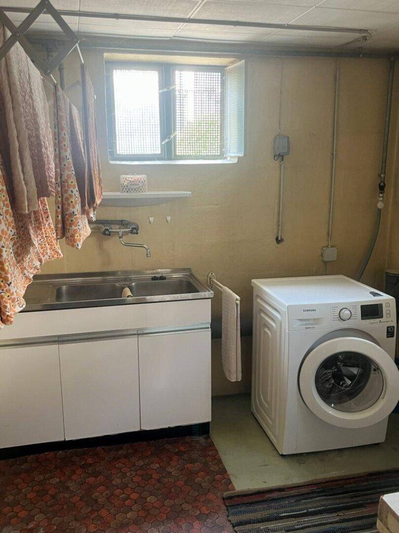 Praktischer Hauswirtschaftsraum mit Waschmaschine, Doppelwaschbecken und Fenster, ideal zum Wäschewaschen.