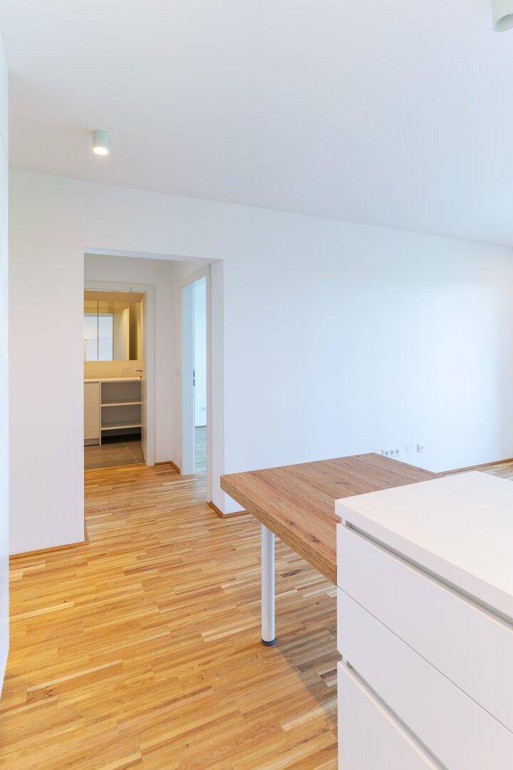 Offener Wohnbereich mit Holztisch und Blick in ein angrenzendes Badezimmer.
