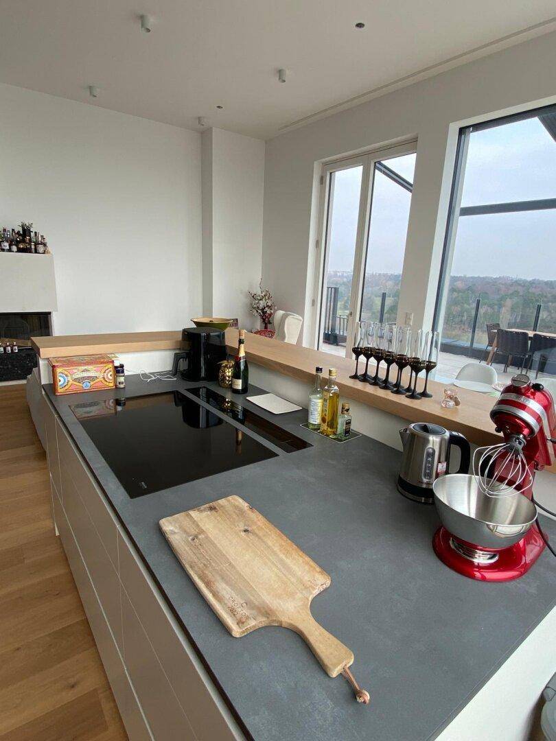 Moderne Kücheninsel mit Induktionskochfeld und Blick auf die umliegende Landschaft.