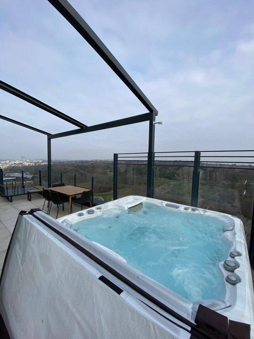 Große Dachterrasse mit Whirlpool und Essbereich, umgeben von einer weiten Landschaft.