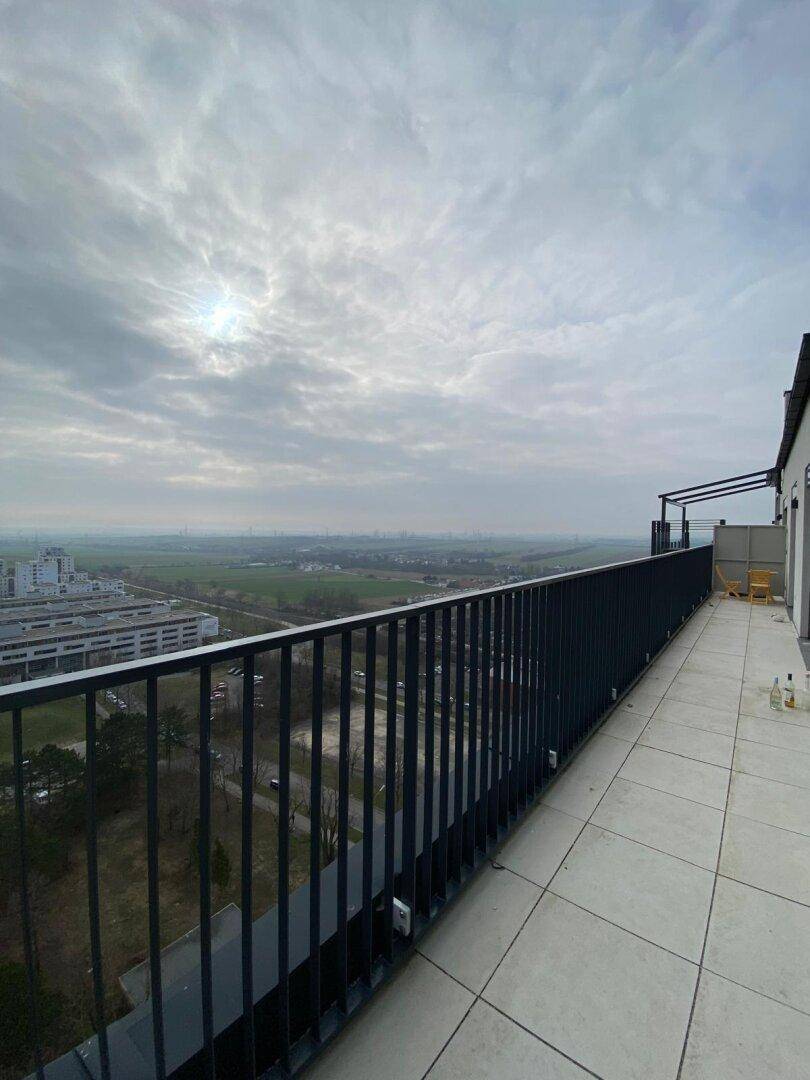 Weitläufige Dachterrasse mit Fliesenboden und weitem Blick über die Umgebung.