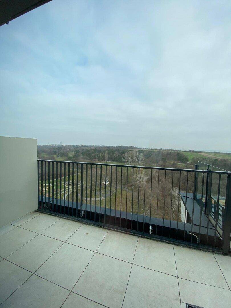 Geräumiger Balkon mit Fliesenboden und Metallgeländer, bietet weite Aussicht.