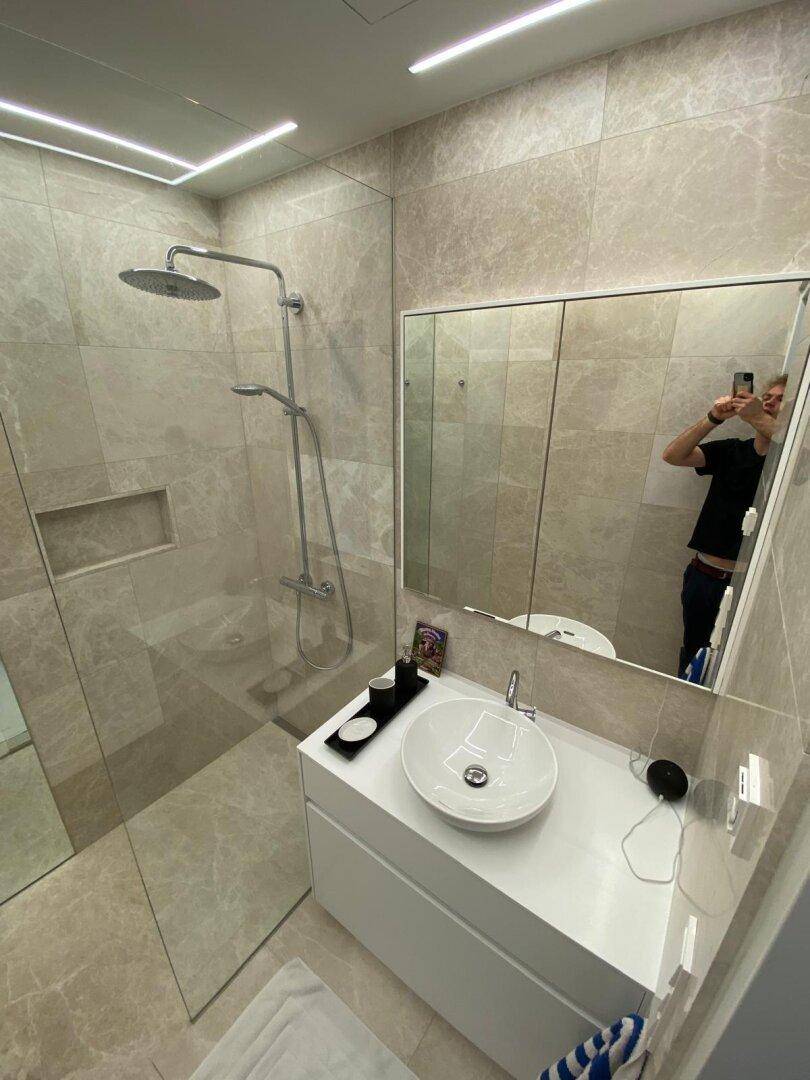 Helles Badezimmer mit begehbarer Dusche, Waschtisch und großem Spiegelschrank.