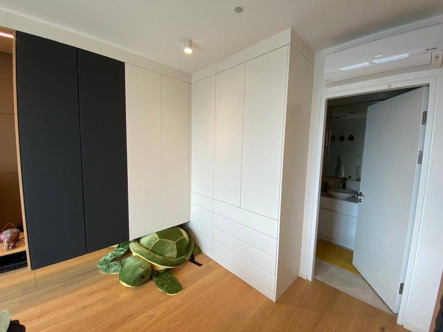 Schlafzimmer mit modernen Einbauschränken und Zugang zu einem angrenzenden Badezimmer.
