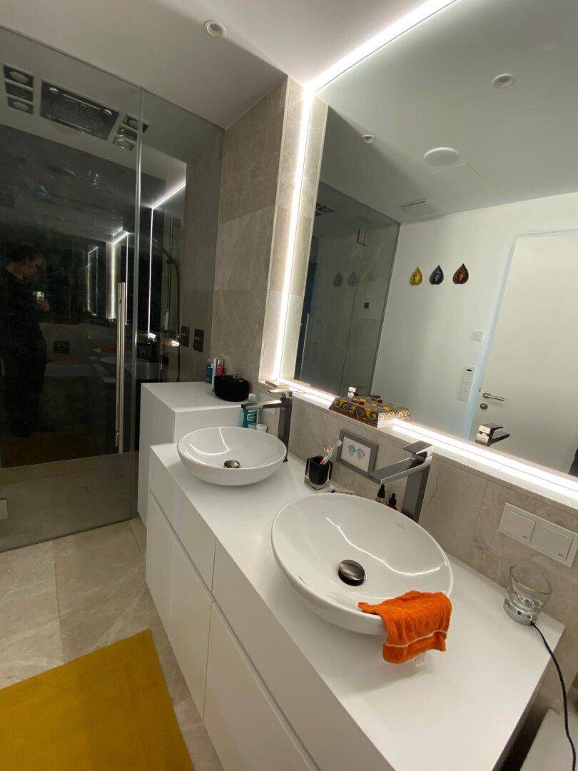 Elegantes Badezimmer mit Doppelwaschbecken, großem Spiegel und moderner Beleuchtung.