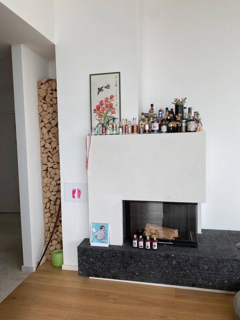 Moderner Kamin mit Holzstapel und minimalistischer Dekoration in einem hellen Raum.